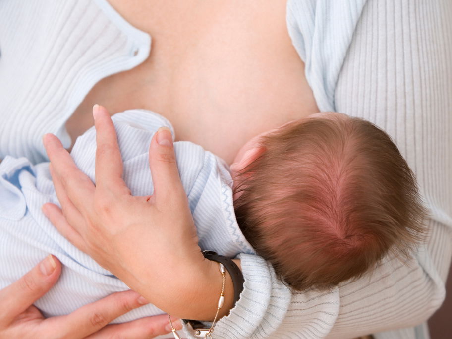 Frau hält Baby beim Stillen.