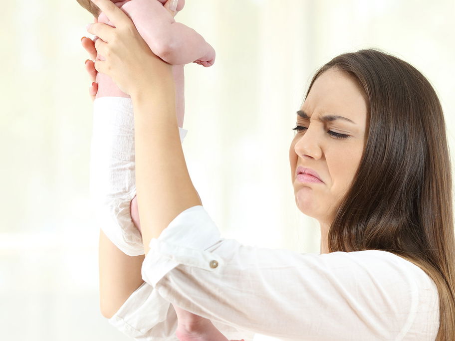 Mutter rümpft die Nase vor der Windel ihres Babys.