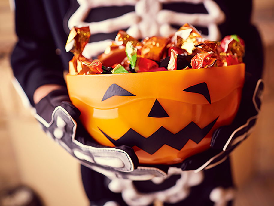 Kind hält Halloween-Schale.