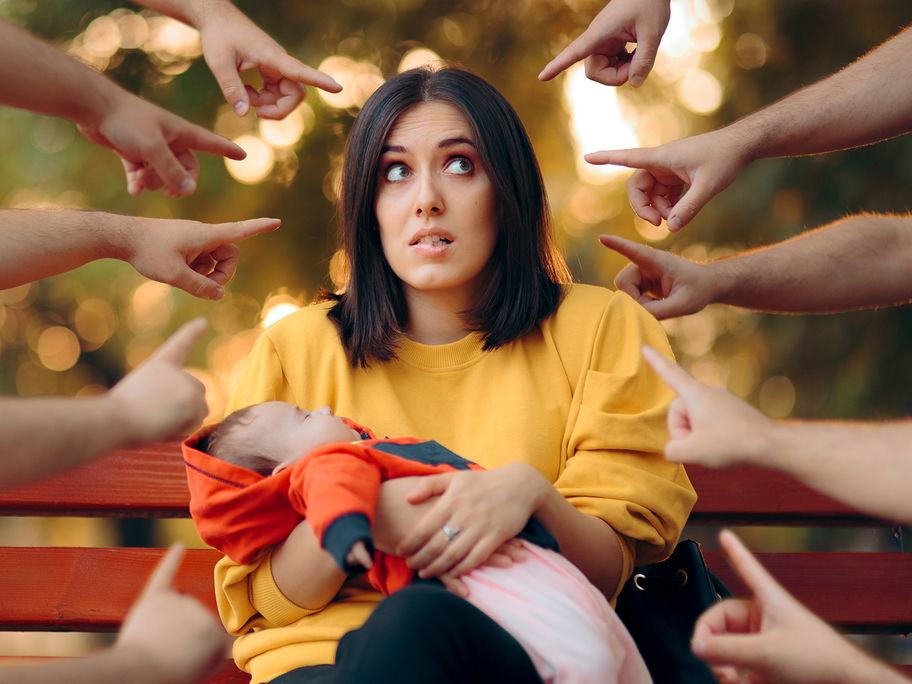 Viele Finger zeigen auf eine Frau mit Baby.