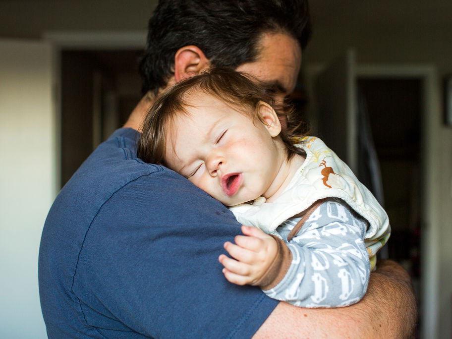 Baby schläft auf Papas Arm.