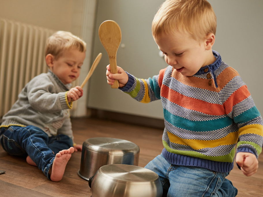 Kinder schlagen mit Kochlöffeln auf Töpfe.