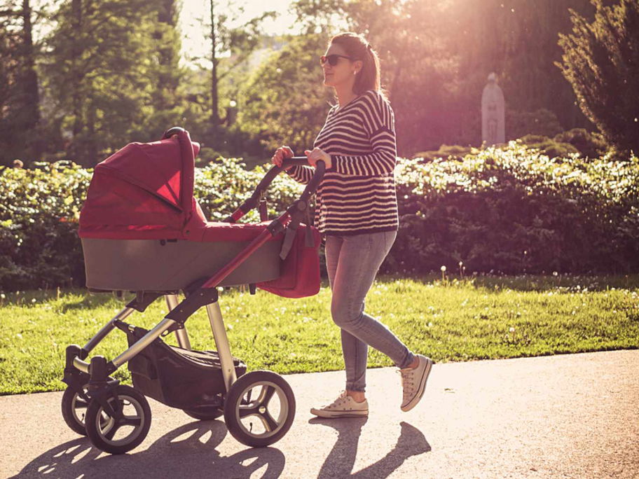 Mutter geht mit Kinderwagen spazieren.