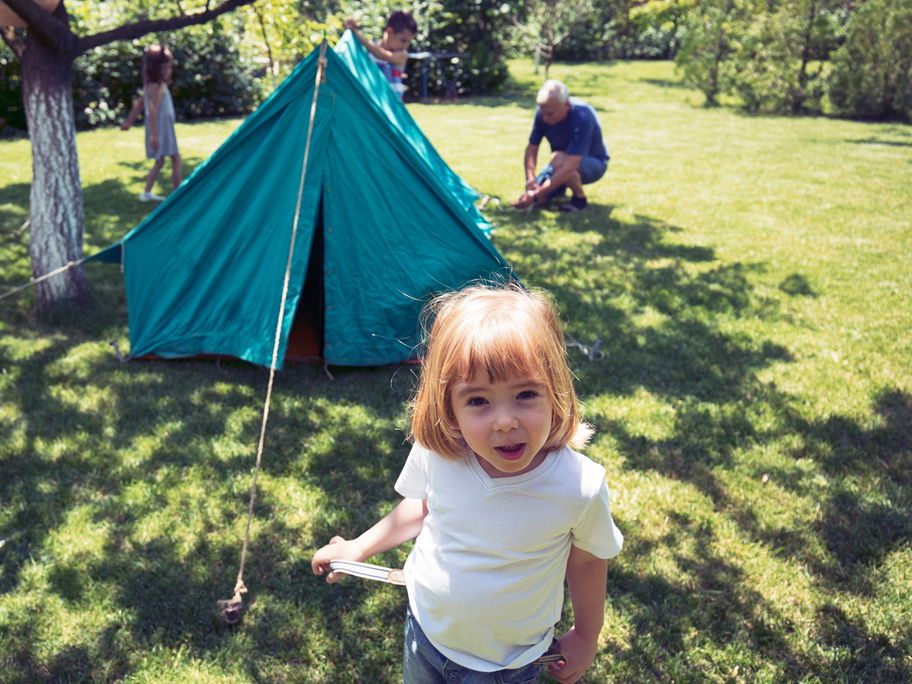 Familie baut ein Zelt im Garten auf.