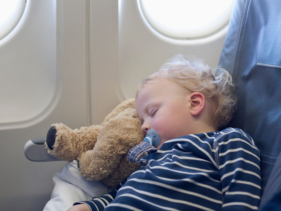 Ein kleiner Junge schläft im Flugzeug.