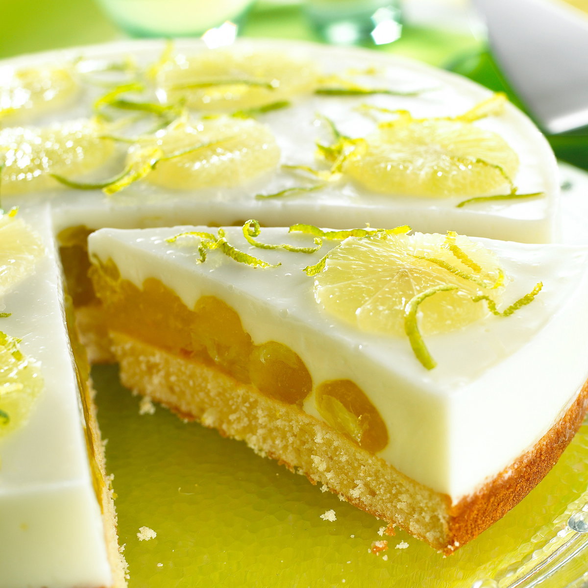 Eine runde Fantatorte mit Limette liegt auf einer Kuchenplatte.