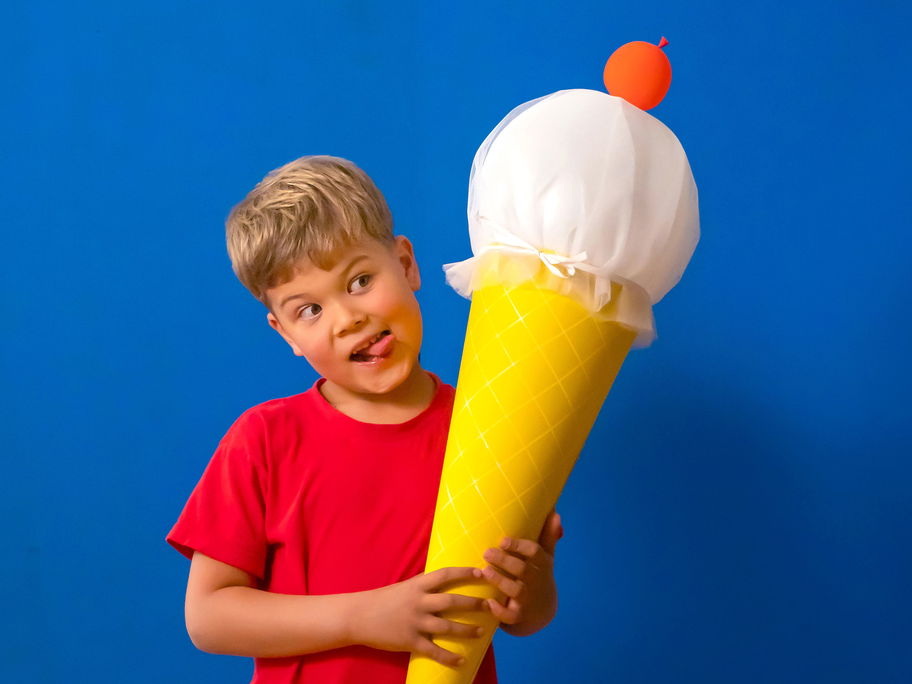 Ein kleiner Junge, der eine selbstgebastelte Eis-Schultüte in der Hand hält.