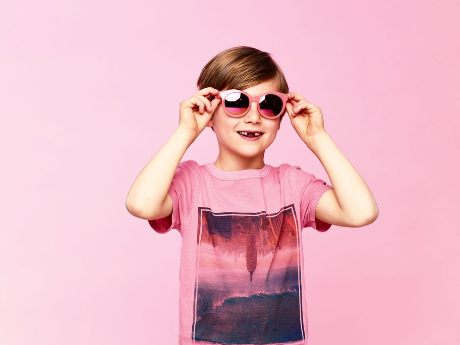Junge mit rosa T-Shirt und rosa Sonnenbrille.