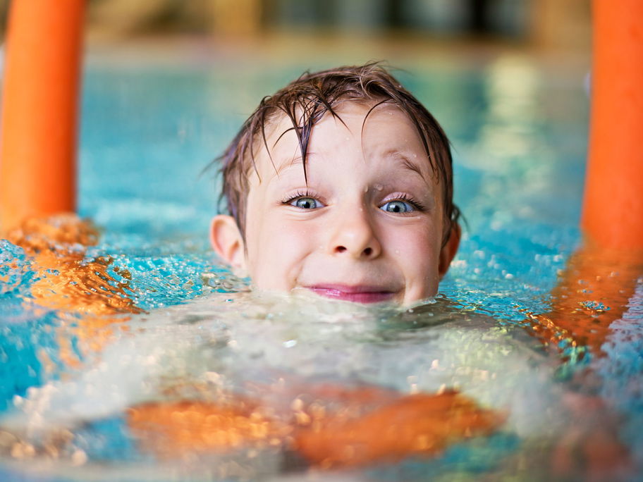 Kind mit Schwimmnudel im Wasser.