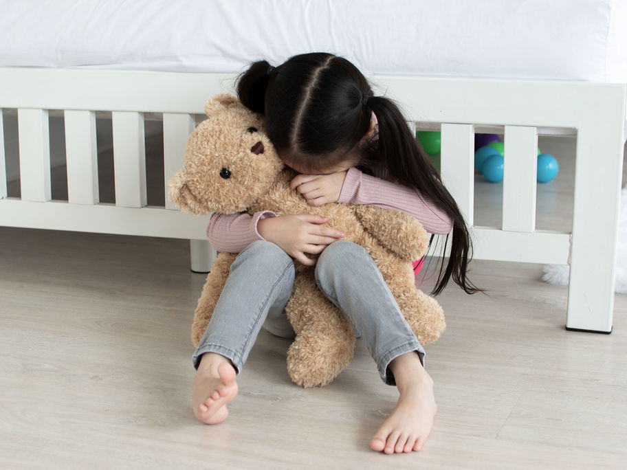 Kind hat Heimweh und weint in seinen Teddy.