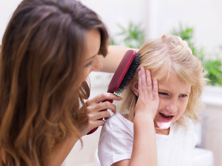 Mutter bürstet ihrem Kind die Haare.