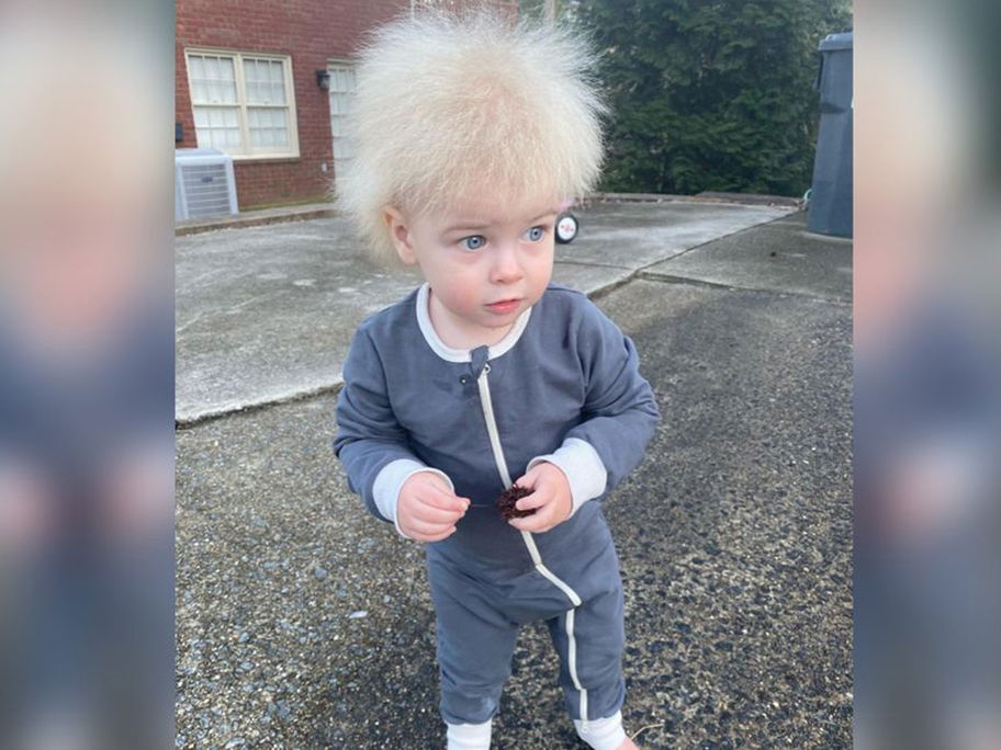 Ein kleiner Junge mit hellem Haar, die zu Berge stehen.
