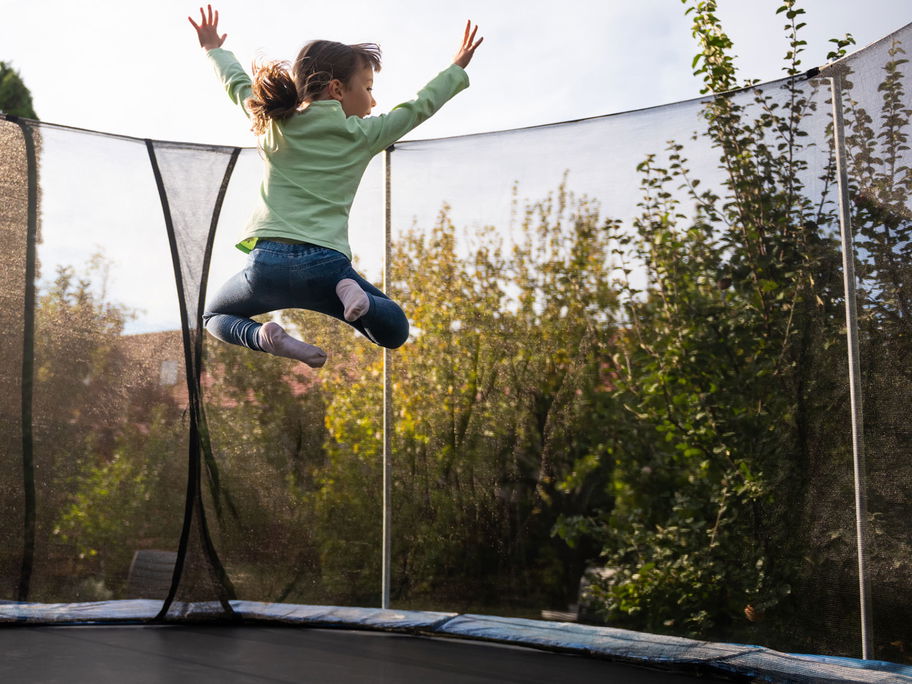 Kind springt hoch auf rundem Trampolin.