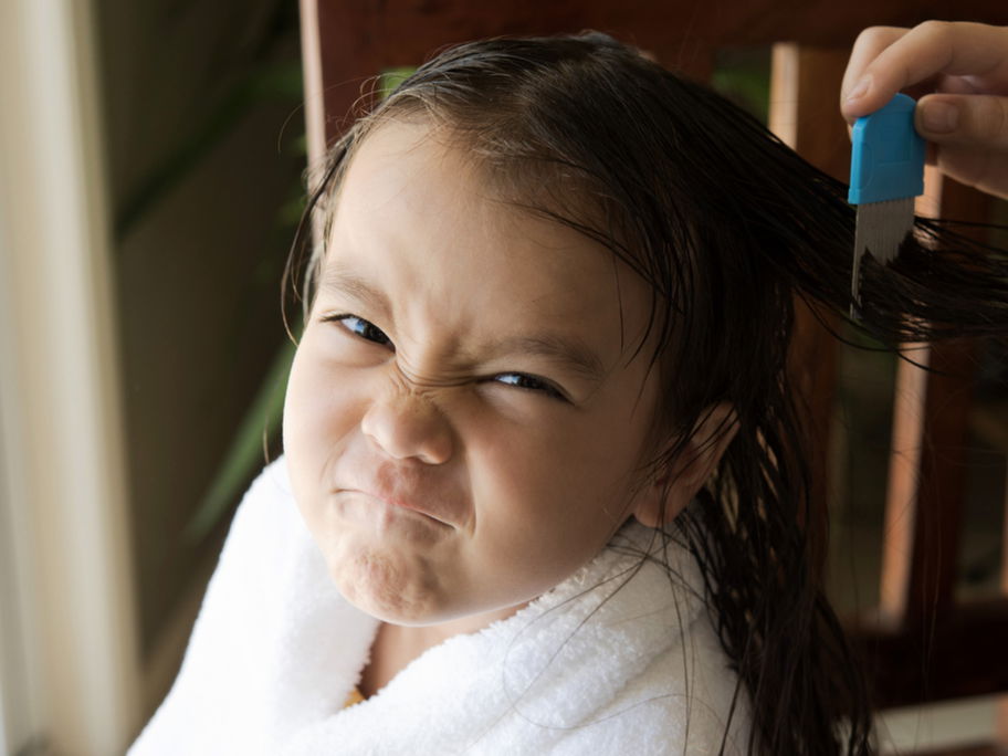 Mutter kämmt die Haare ihres Kindes mit einem Läusekamm aus.