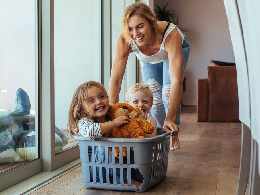 Mutter schiebt ihre Kinder im Wäschekorb.