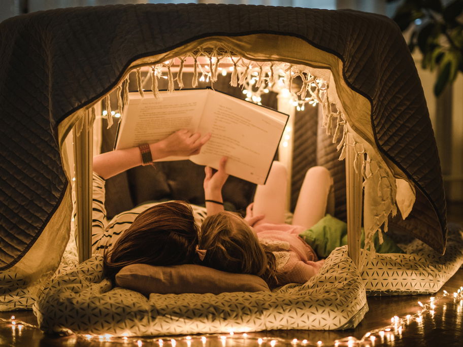 Mutter und Kind lesen Märchen in einer Höhle in der Wohnung.