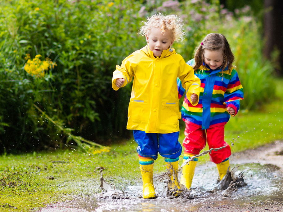 Kinder spielen in Pfützen.