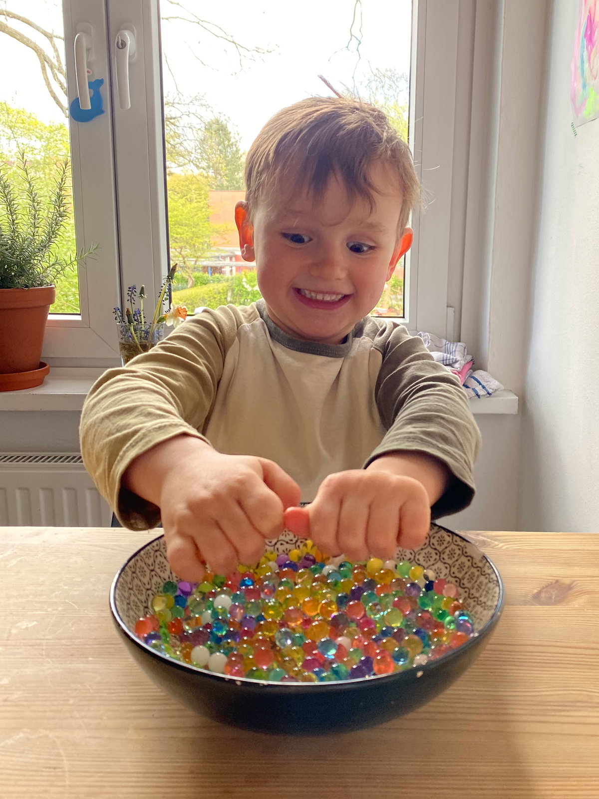 Ein kleiner Junge spielt mit Wasserperlen.