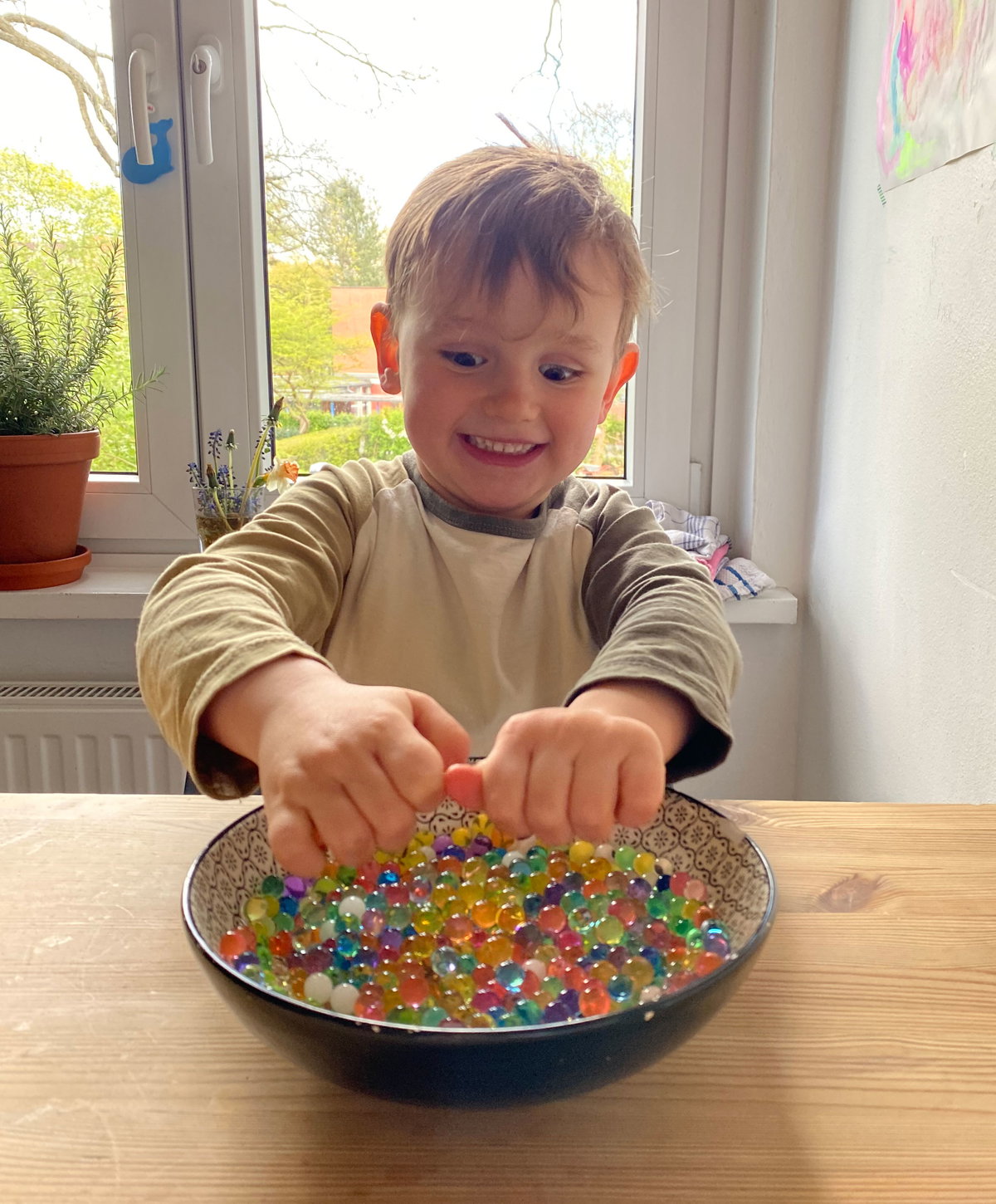 Ein kleiner Junge spielt mit Wasserperlen.