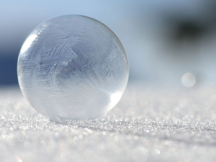 Eine gefrorene Seifenblase liegt auf einer Eisfläche.
