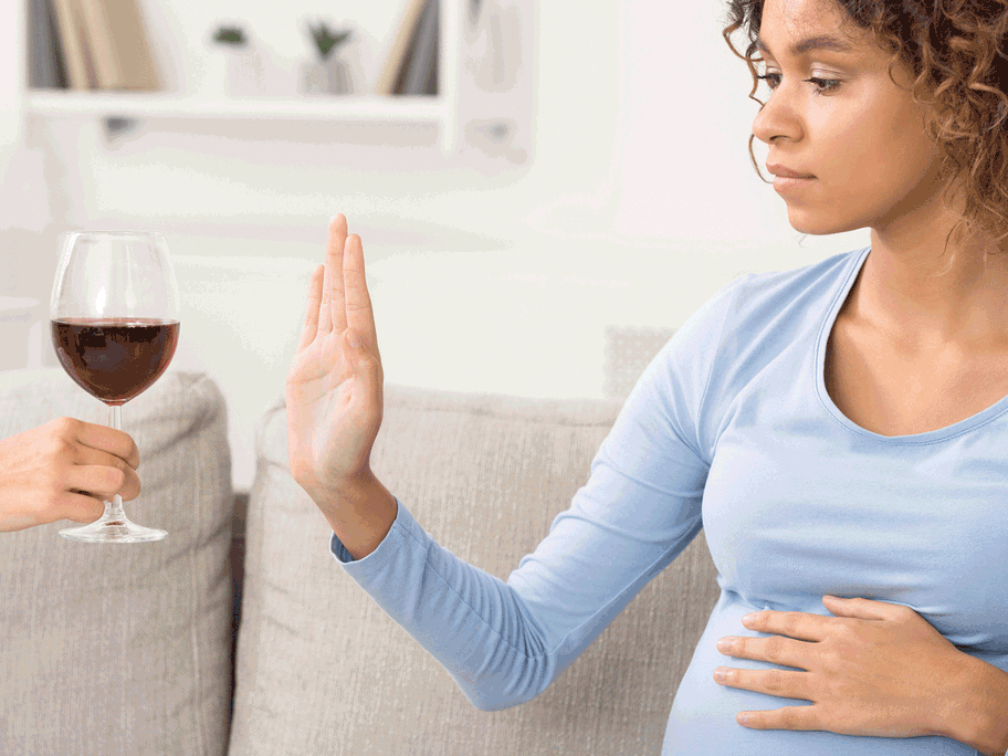 Schwangere Frau lehnt ein Glas Wein ab.