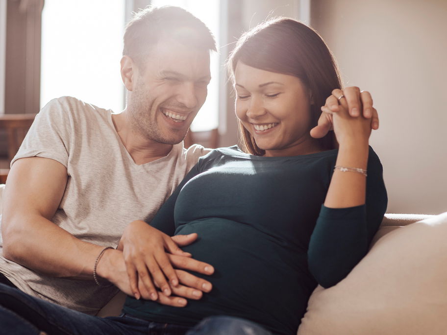 Paar streichelt den Babybauch.
