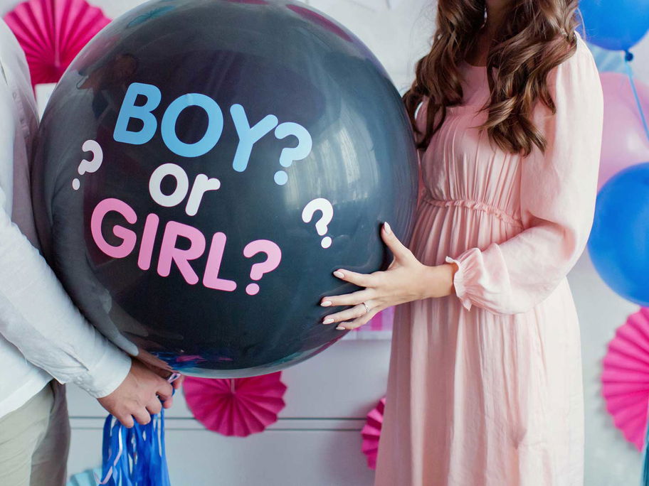 Werdende Eltern halten großen Ballon mit Aufschrift "boy or girl?".