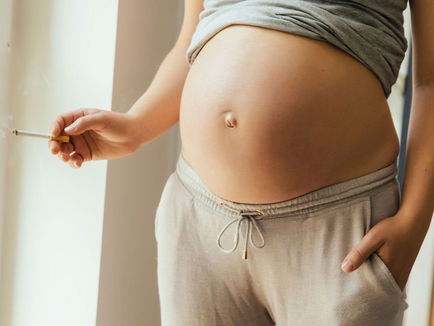 Frau mit Babybauch und Zigarette