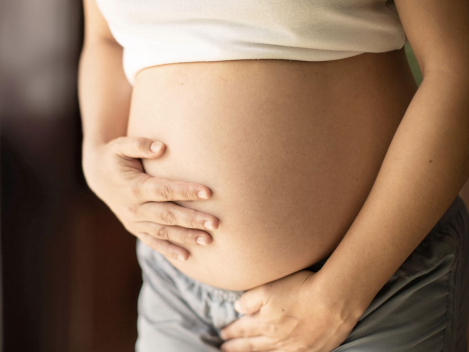 Schwangere hält sich den Bauch und die Blase.
