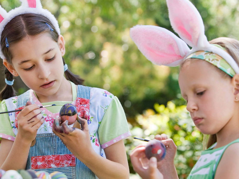 Zwei Kinder bemalen Ostereier im Garten.